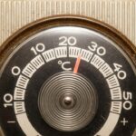 Close-up of a vintage thermostat displaying temperature settings.