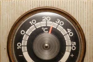Close-up of a vintage thermostat displaying temperature settings.