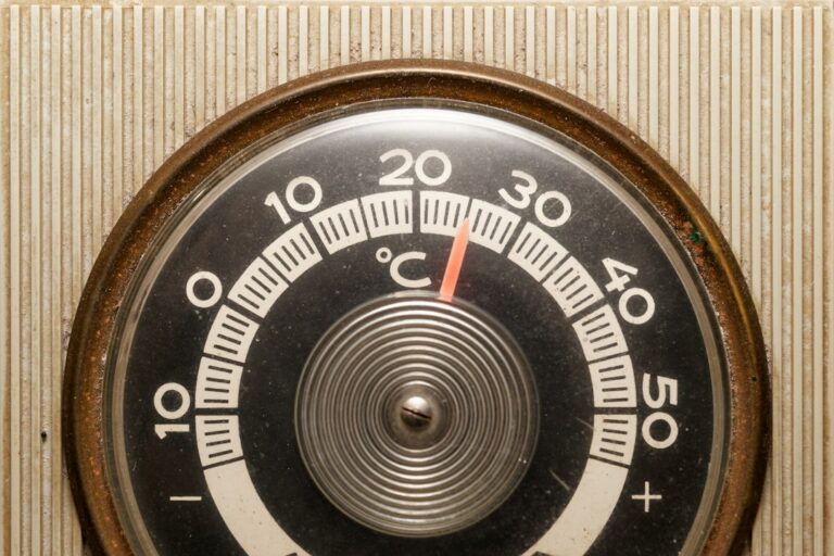 Close-up of a vintage thermostat displaying temperature settings.